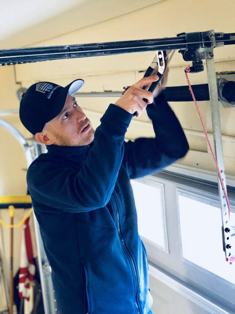 Garage door technician repairing opener and overhead door components