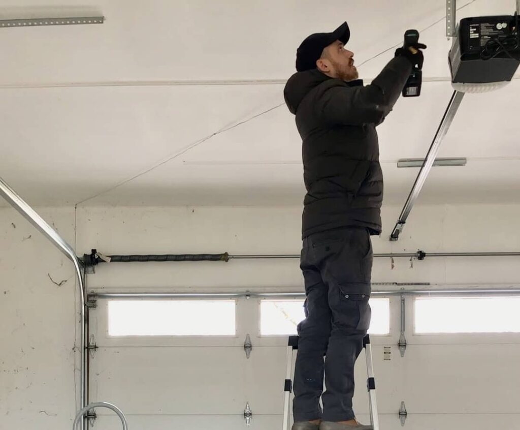 Technician installing garage door opener in residential garage