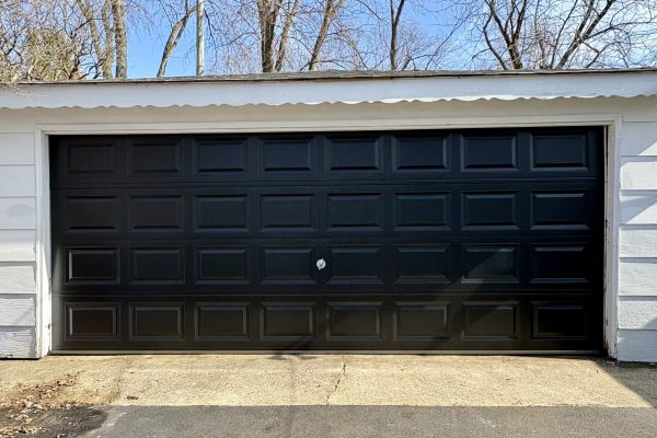 Black residential garage door needing professional repair service